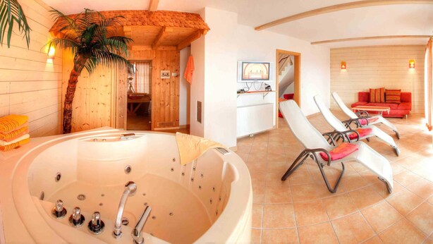 Ein Zimmer mit einer großen Badewanne, einem roten Sofa und einer Holzwand.