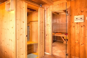 Une cabine de sauna en bois, équipée d’un banc, d’un porte-serviettes et d’une porte de sauna.