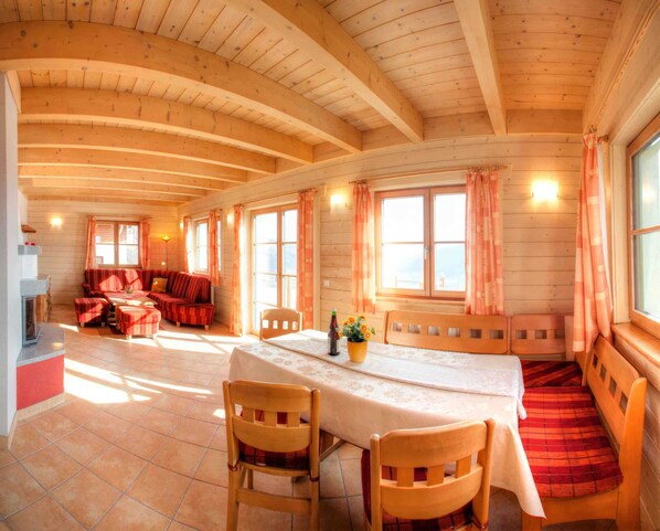 Una cabaña acogedora de madera con comedor, sofá y chimenea.