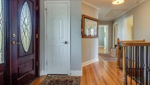 A wooden front door with glass panels, a white interior door, and a staircase with a wooden railing. - Enjoy fireside sunset & walk to movies, shops, restaurants! (Winchester)