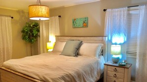 A neatly arranged bedroom with a wooden bed, bedside lamps, a nightstand, and a potted plant. - Enjoy fireside sunset & walk to movies, shops, restaurants! (Winchester)