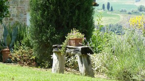 A garden with a stone wall, various plants, and a view of the countryside. - Podere Poggio al Sole (Montepulciano)