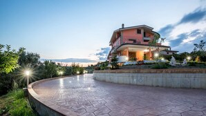 Una casa de dos pisos con un camino de entrada curvo y un jardín ajardinado.