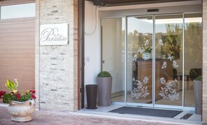 A restaurant entrance with a sign reading "B&B Paradiso," a glass door with decorative butterfly stickers, and potted plants outside. - B&B Paradiso (Vasto)