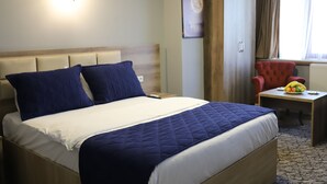 A hotel room with a bed, a desk, a chair, and a window with curtains. - Kocatepe Hotel (Ankara)