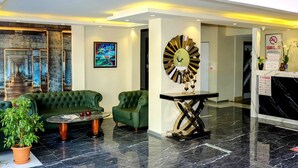 A lobby with a green sofa, a round table, a clock, and a staircase. - Kocatepe Hotel (Ankara)