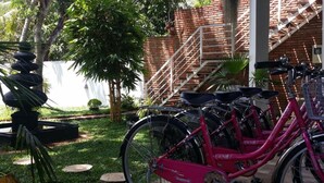 Een rij roze fietsen geparkeerd in een buitengebied met een bakstenen muur en een trap op de achtergrond.