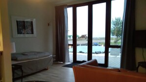 Una habitación de hotel con cama, sofá y un amplio ventanal con vistas al exterior.