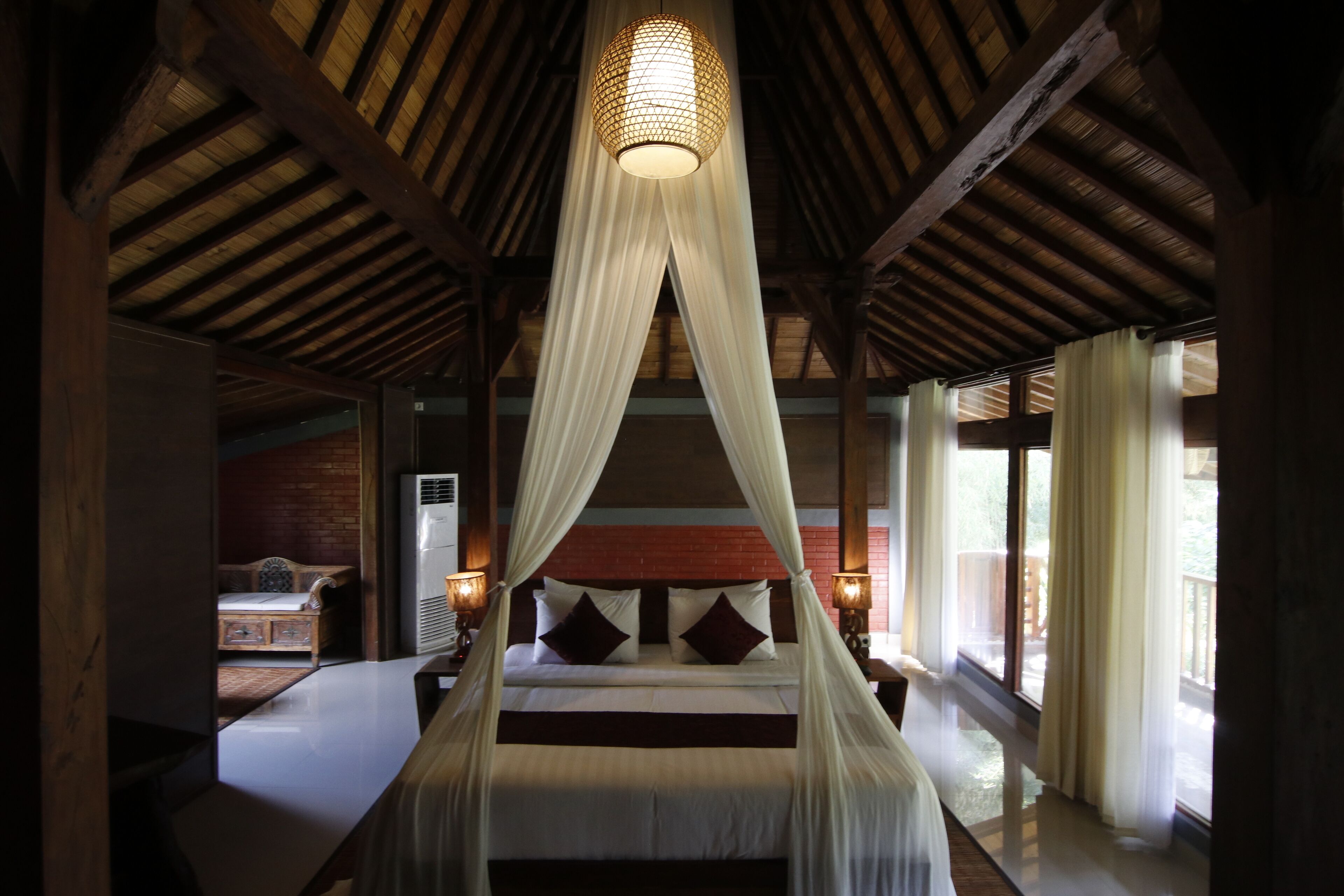 Een ruime slaapkamer met een groot bed, een hemelbed en uitzicht op de omgeving.