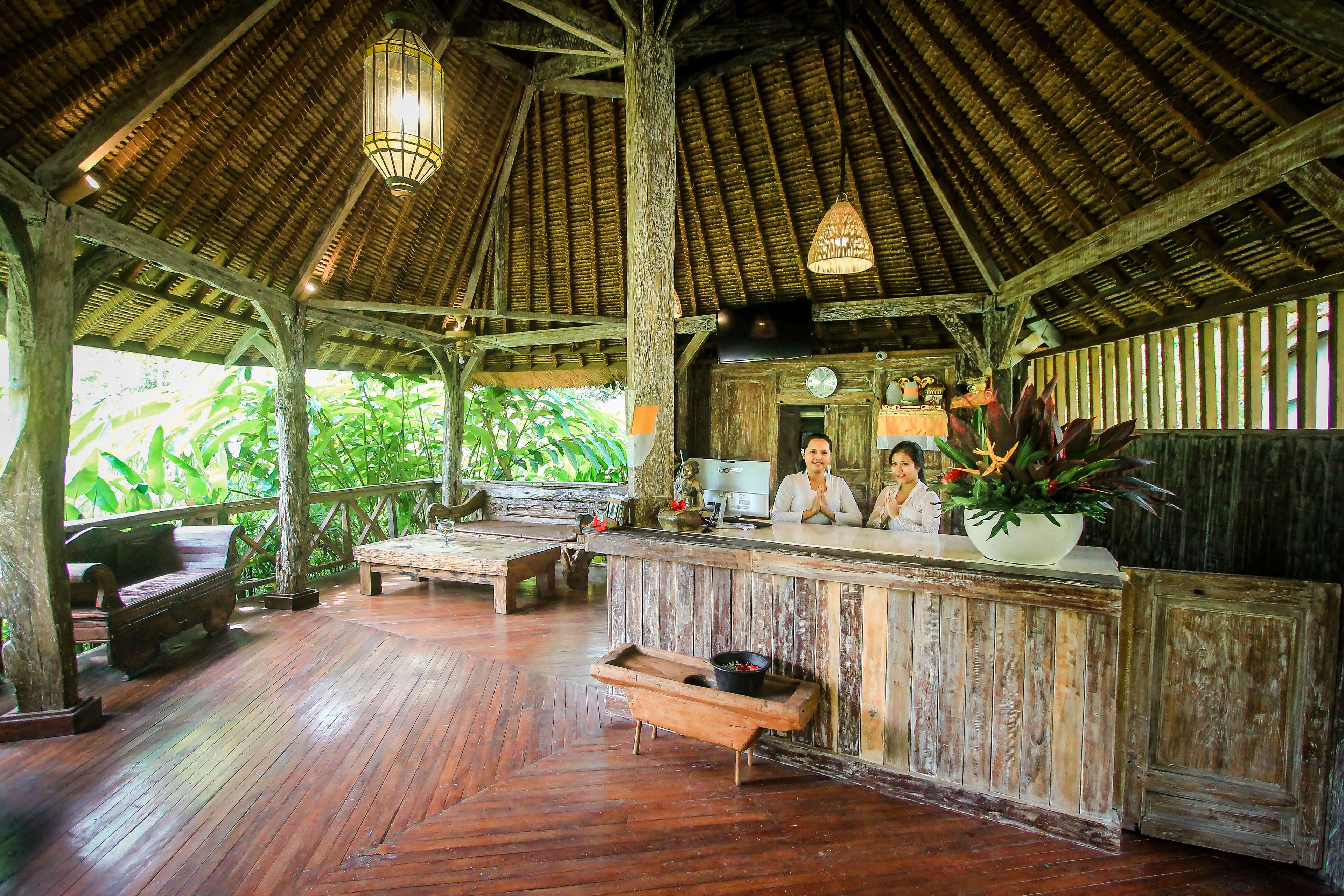 Un interior rústico de madera con una zona de bar, mobiliario de madera y un techo de paja.