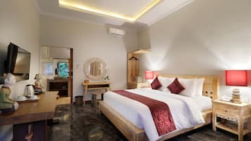 Quarto de hotel com cama, mesa de cabeceira, escrivaninha e televisão.