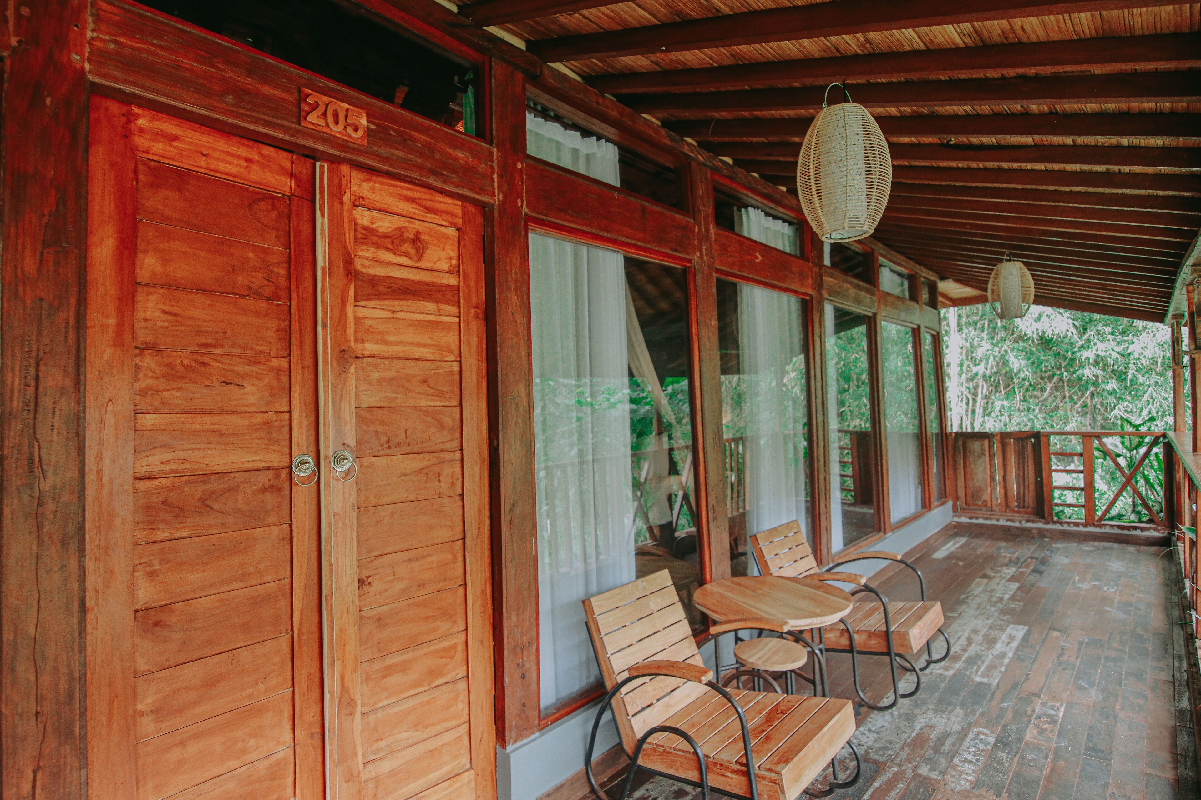 A wooden porch with a covered roof, wooden doors, and a table with chairs.