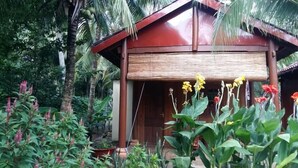 Une structure en bois surmontée d’un toit rouge, entourée d’une vég étation luxuriante et de plantes en fleurs.