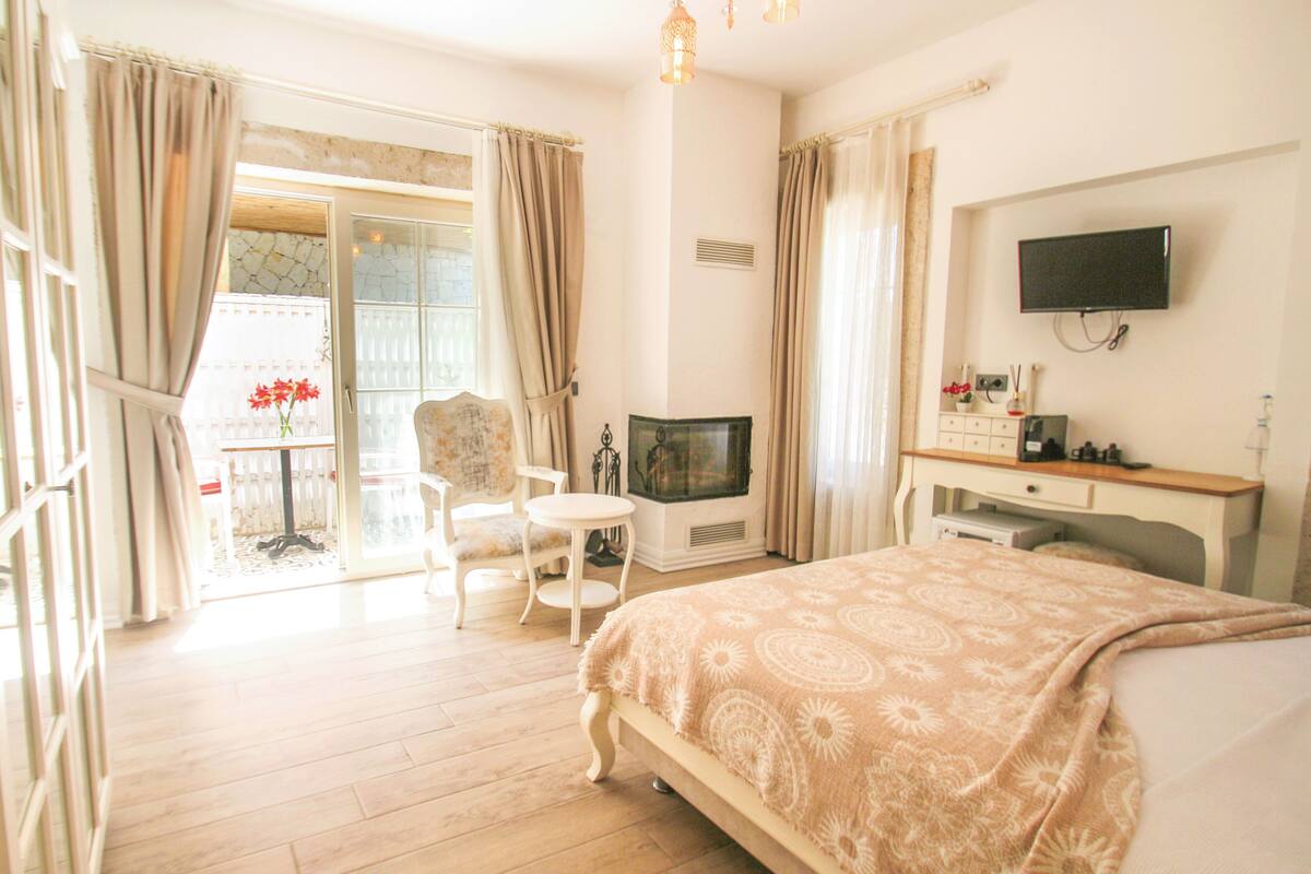 A hotel room with a bed, a TV, a desk, a chair, and a view of the outside.