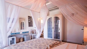 A bedroom with a canopy bed, a wardrobe, a desk, and a chair.