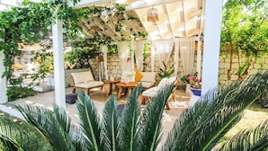 A covered patio with white columns, a wooden table, and chairs.