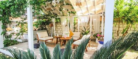 A covered patio with white columns, a wooden table, and chairs.