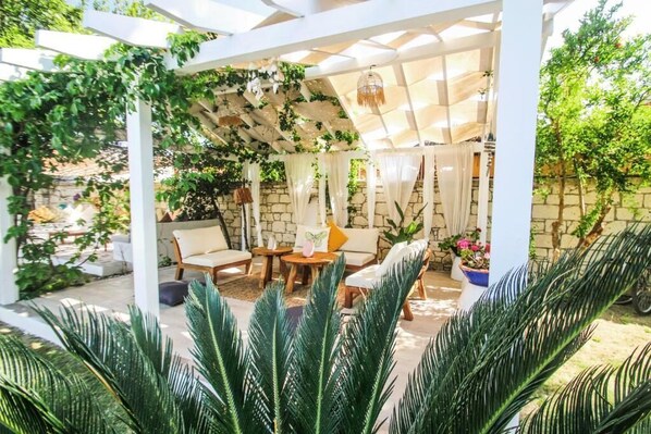 A covered patio with white columns, a wooden table, and chairs.