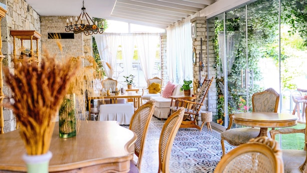 A dining area with a stone wall, wooden furniture, and a large window with curtains.