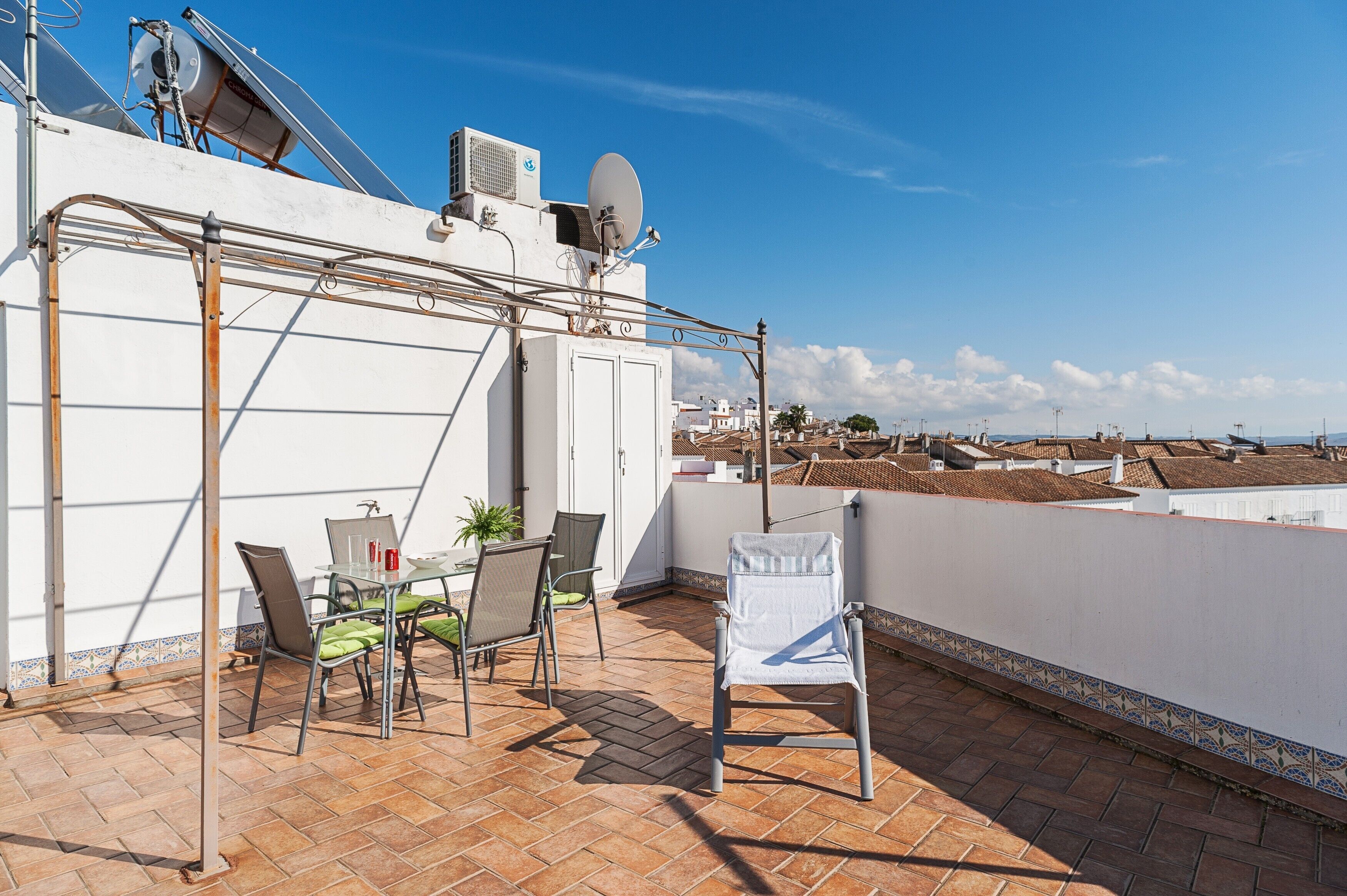 Eine Dachterrasse mit Tisch, Stühlen und Blick auf die Stadt.