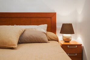 A bed with a wooden headboard, a bedside lamp, and a nightstand with drawers.