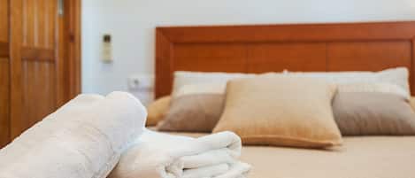 A neatly made bed with a wooden headboard, two pillows, and a folded white towel.