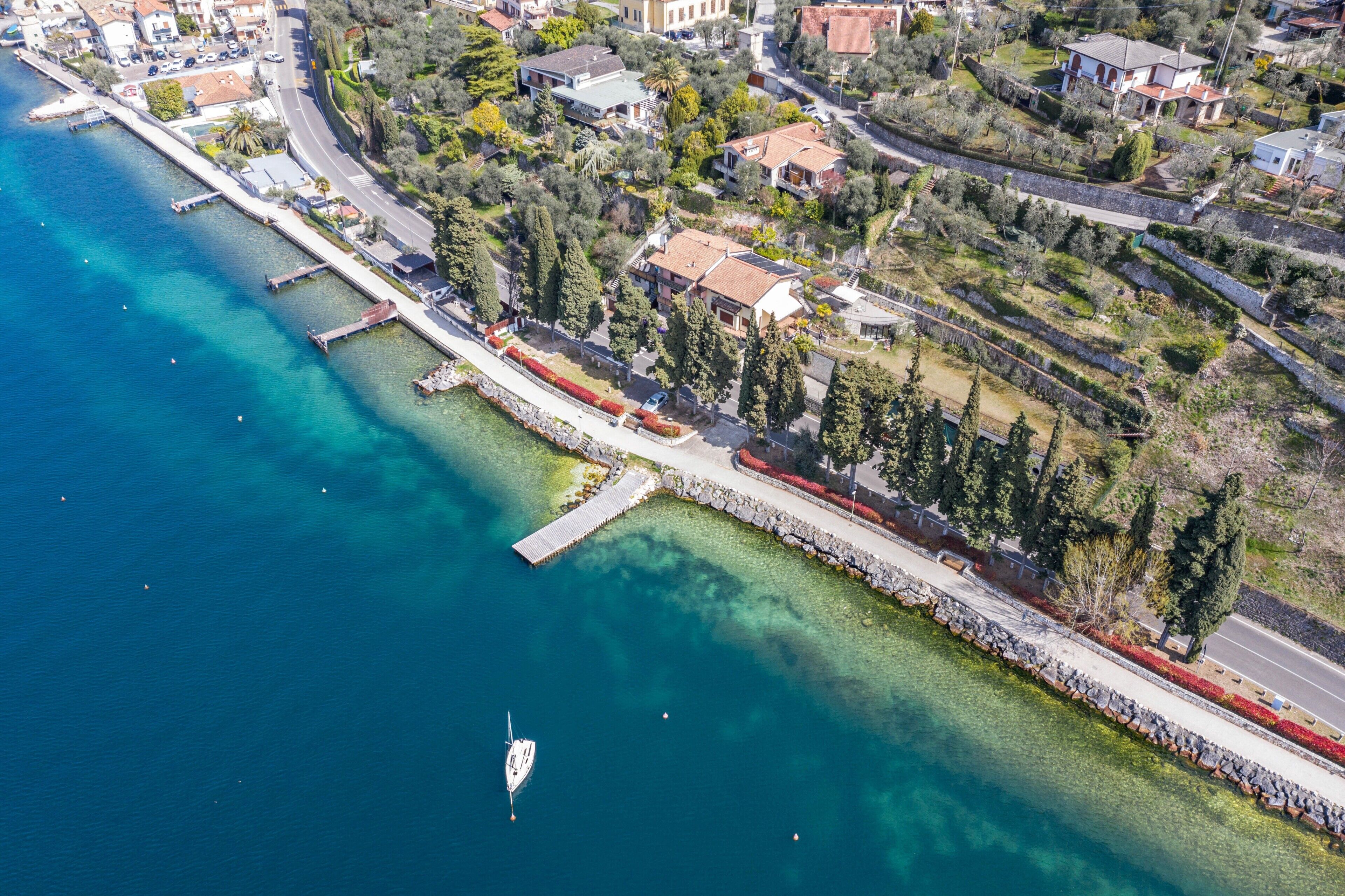 An aerial view of a coastal town with a marina, waterfront promenade, and residential buildings.