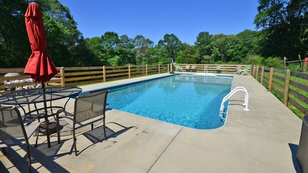 A rectangular swimming pool with a wooden deck and metal chairs. - She's back! Under new management (Cullman)