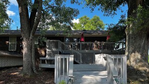 A wooden deck leading to a covered porch with a staircase. - She's back! Under new management (Cullman)