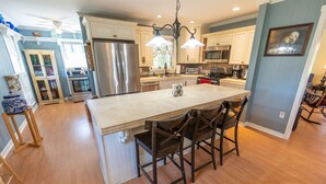 A spacious kitchen with a central island, stainless steel appliances, and a chandelier. - She's back! Under new management (Cullman)