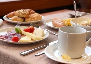 Une table dressée pour le petit-déjeuner, avec des assiettes de nourriture, une tasse et des couverts.
