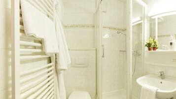 A modern bathroom with a glass-enclosed shower, a white toilet, and a sink with a mirror above it.