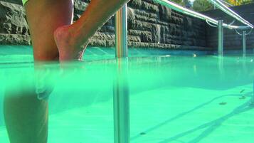 Una piscina con agua cristalina y barandales de metal.