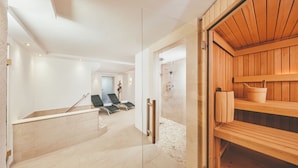 Ein moderner Wellnessbereich mit Sauna, einer Rezeption und einer Sitzecke mit Stühlen.