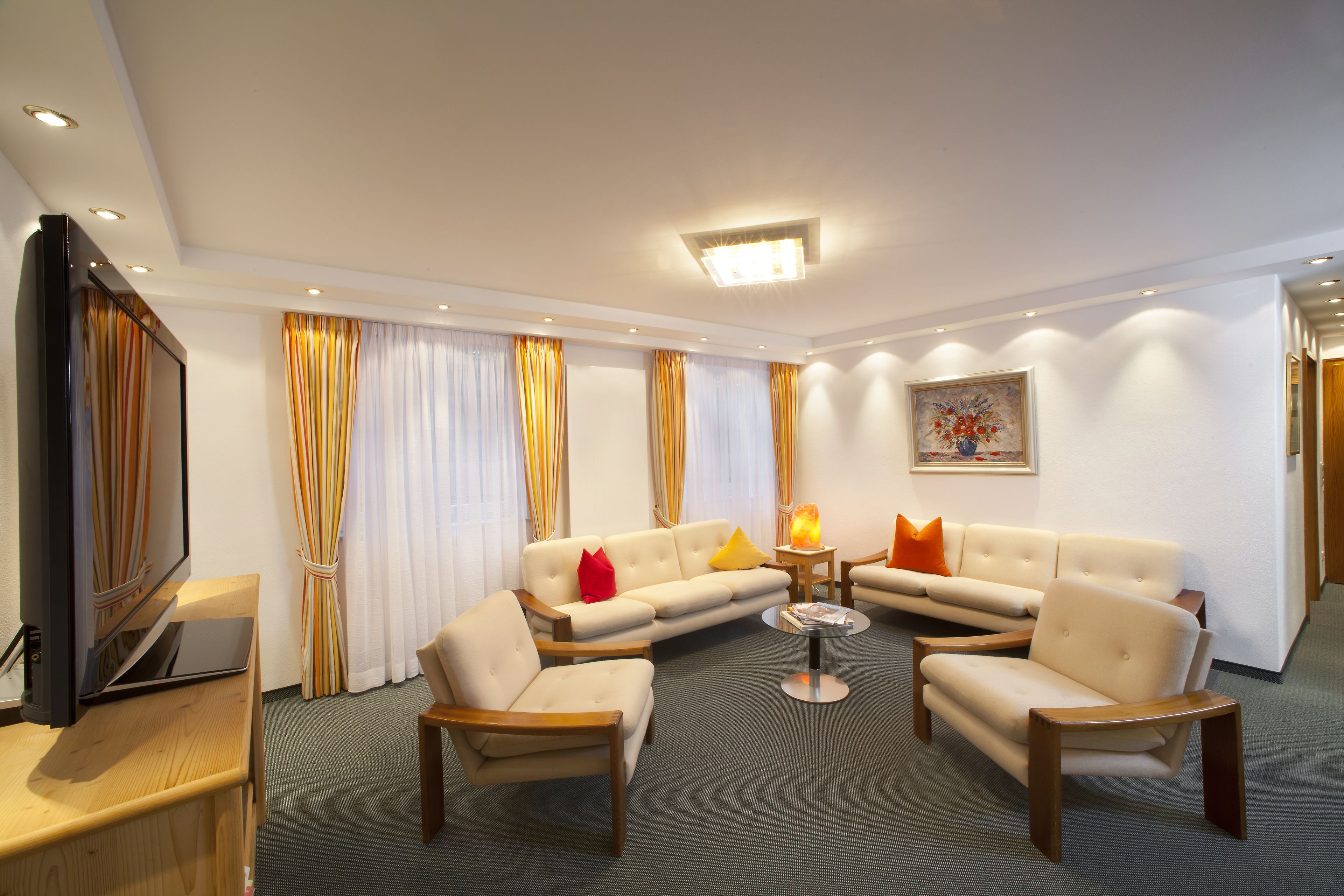 Una sala de estar moderna con un televisor de pantalla plana, sofás color beige, una mesa de centro de madera y un cuadro en la pared.