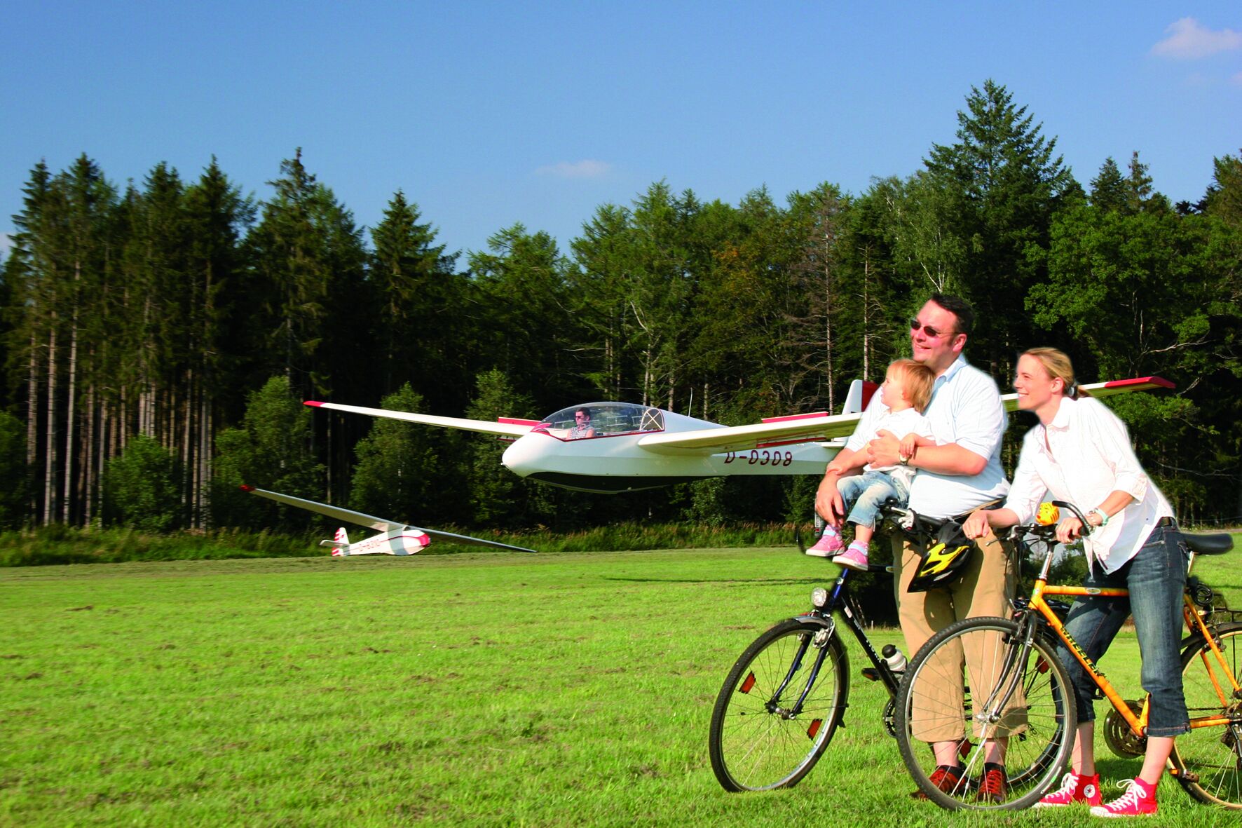 A grassy field with a small aircraft and two bicycles.