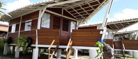 A wooden house with a tiled roof, a wooden staircase, and a small garden area.