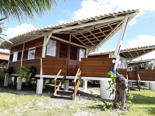 A wooden house with a tiled roof, a wooden staircase, and a small garden area. - Pousada Vettore (Barreirinhas)