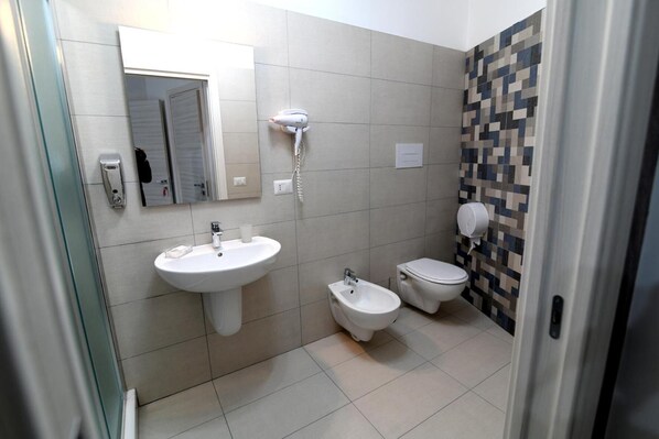 Un baño con lavamanos, bidé, inodoro y espejo.