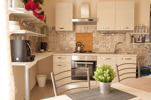 Una cocina moderna con armarios blancos, una campana extractora de acero inoxidable, un horno empotrado y una encimera de madera.