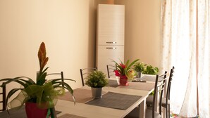 Uma sala de jantar com uma mesa, cadeiras, plantas em vasos e um armário branco.