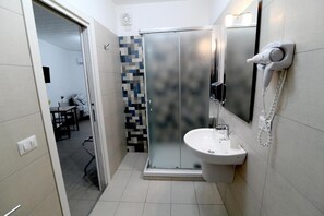 A modern bathroom with a shower, a sink, and a hairdryer mounted on the wall. - La Regina di Saba (Piazza Armerina)