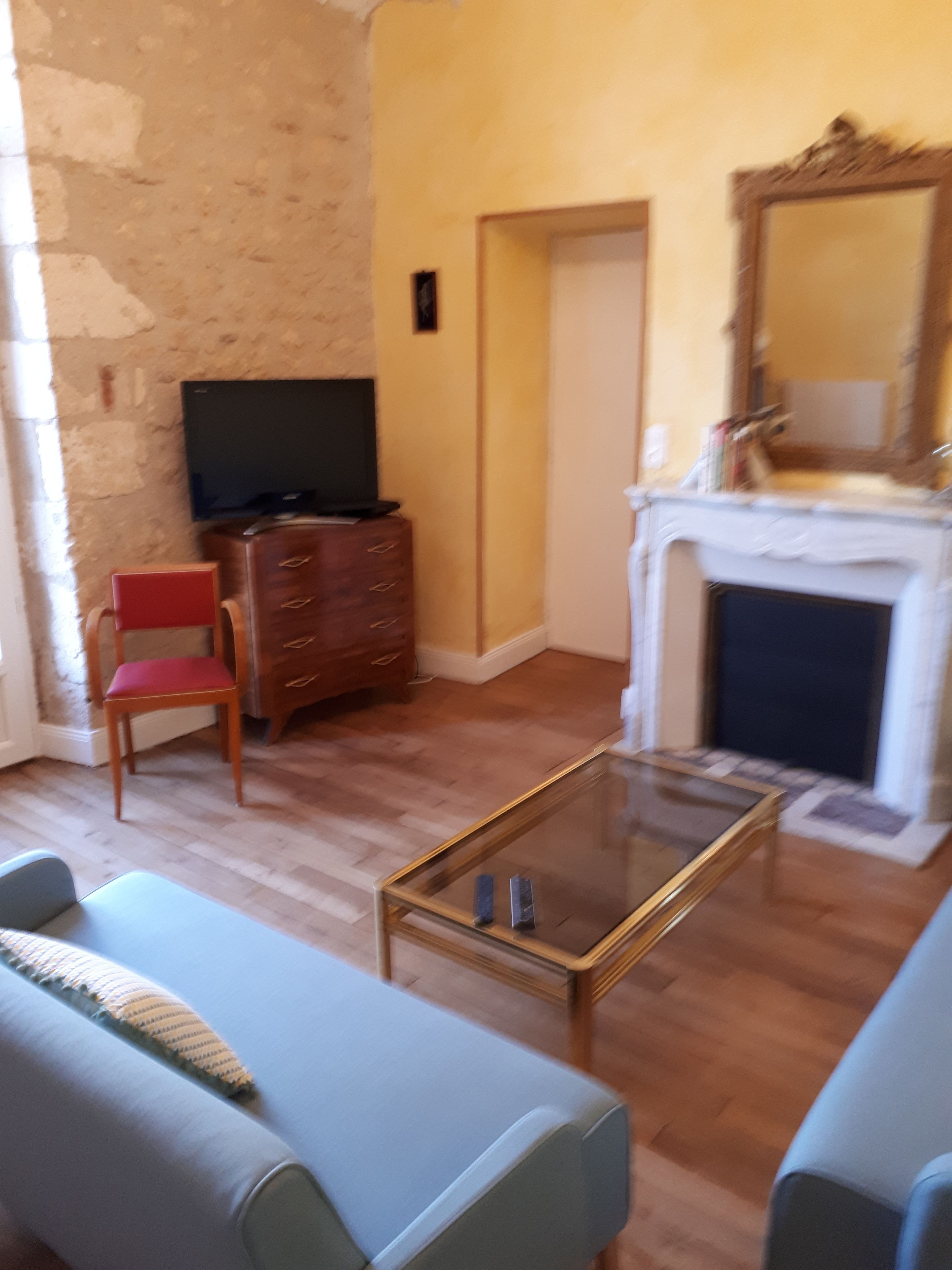 Een woonkamer met een televisie, een open haard en een rode stoel.