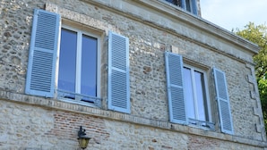 A stone building with a wooden door, two windows with shutters, and a small balcony. - Villa du Cerf Thibault (Le Blanc)