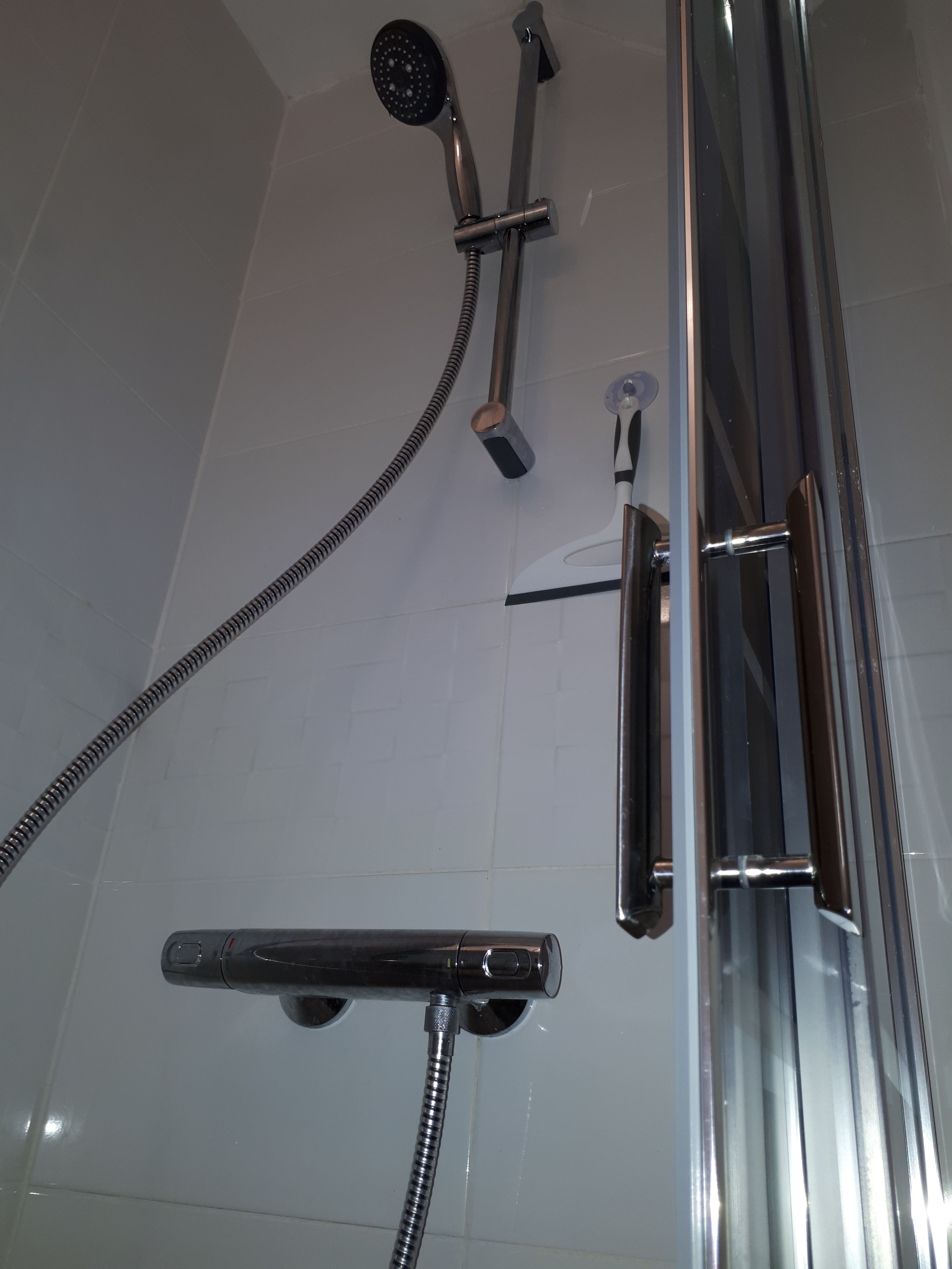 Une douche équipée d’un pommeau de douche à main, d’un flexible de douche et d’un tuyau flexible.