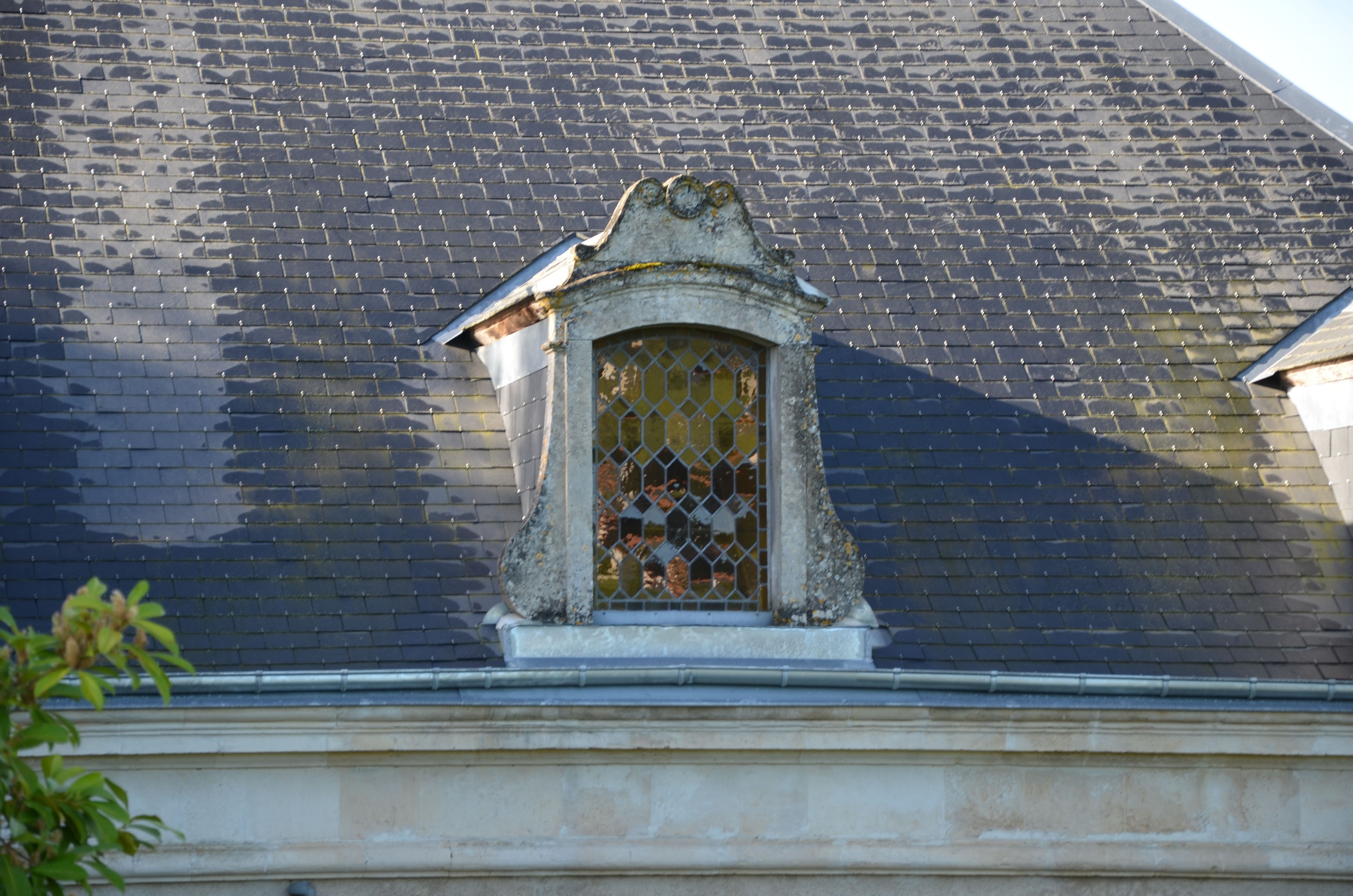 A building with a tiled roof and a small window with a decorative frame.