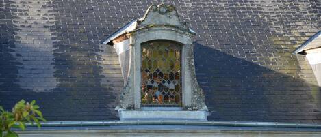 A building with a tiled roof and a small window with a decorative frame.