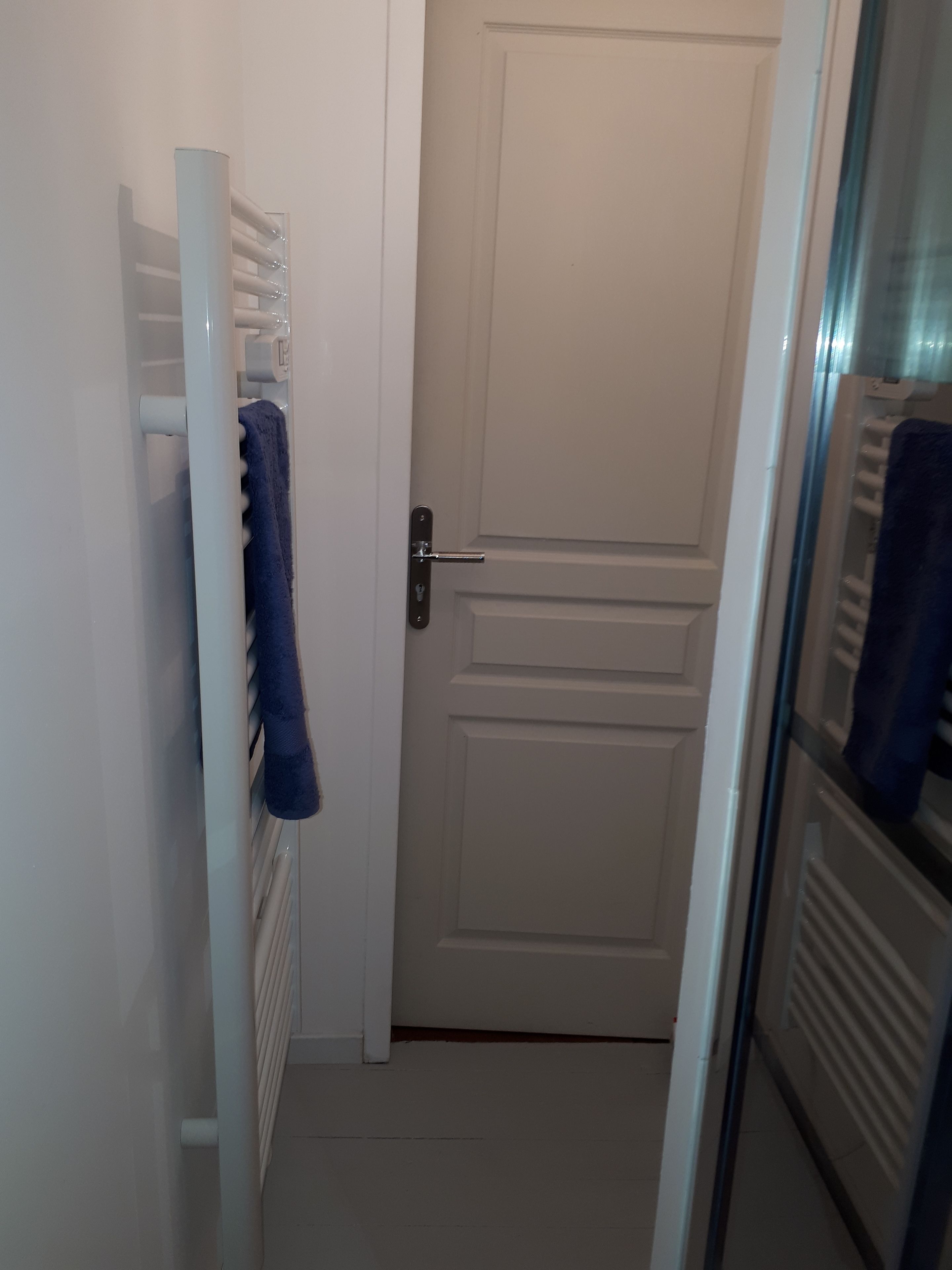 A white door with a handle, a towel hanging on a rack, and a radiator.
