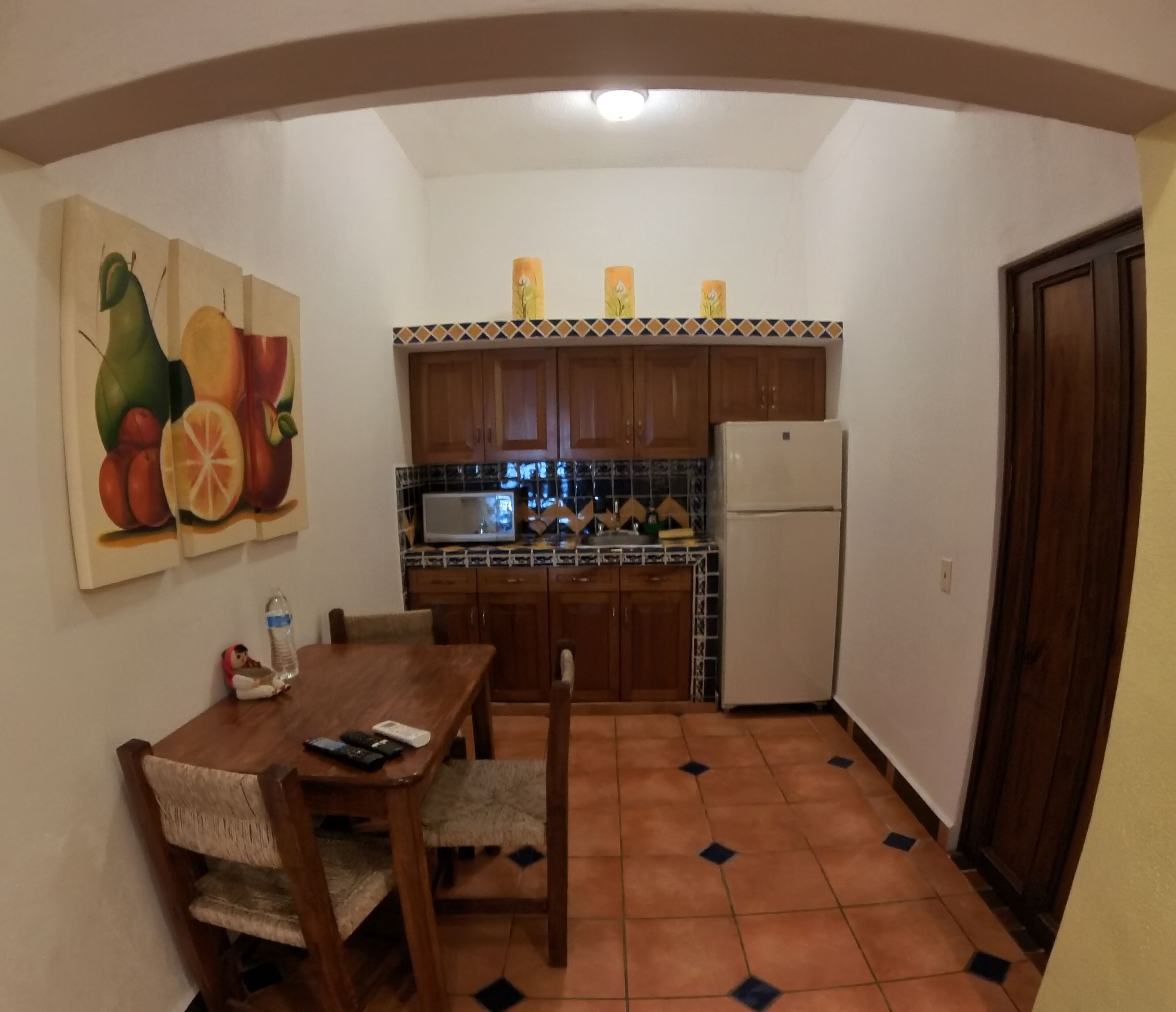 A compact kitchen with wooden cabinets, a white refrigerator, and a tiled backsplash.