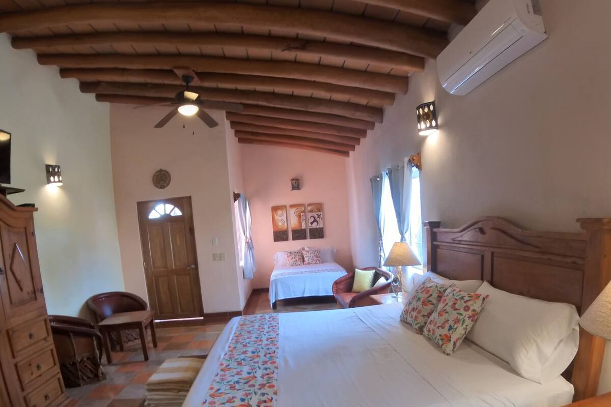 A bedroom with a large bed, a wooden headboard, a ceiling fan, and a nightstand.